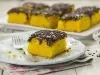 Foto de um pedaço de bolo de cenoura com cobertura de brigadeiro em um prato branco com um garfo do lado