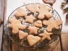 Em cima de uma mesa, grade com biscoitos em formato de coração, estrelas e bonecos de gengibre.