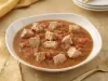 Goulash moderno de atum servido em prato fundo, com cubos de peixe em molho de tomate encorpado e ervas frescas.