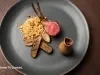 Costeletas de cordeiro com farofa de castanhas, legumes grelhados e molho escuro em prato de apresentação.