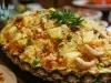 Em um abacaxi cortado ao meio, porção de arroz com abacaxi picados, ervilhas, cenouras em cubos e castanha-do-Pará.