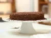 Imagem de um bolo redondo coberto com chocolate granulado sobre uma boleira branca.