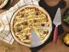 Imagem vista de cima de uma pizza redonda de frango com catupiry, milho e azeitonas em uma forma de alumínio.