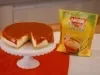 imagem mostra uma cheesecake cremosa de milho com cobertura de goiabada em uma forma redonda.