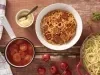 Imagem vista de cima de um prato branco com macarrão com molho de calabresa. Ao lado, uma panela de macarrão, uma panela de molho e um potinho de queijo ralado.