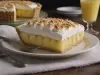 Fotografia de uma fatia grande de uma torta de abacaxi com o chantilly maçaricado por cima. A fatia está sobre um prato branco e raso de vidro.