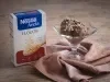 Foto da receita de sorvete de banana, cacau e aveia servida em uma taça de vidro sobre um pano marrom claro em cima de uma mesa de madeira