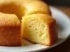 Fotografia de um bolo bundt recém-assado, com crosta dourada e interior macio, apresentado em um prato branco. A textura é suave e esponjosa, destacando um aspecto caseiro e apetitoso.
