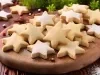 Em cima de uma mesa, prato com biscoitos em formato de estrelas, polvilhados com açúcar de confeiteiro.