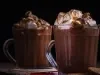 Receita de smorecaccino servida em duas canecas de vidro sobre uma mesa de madeira