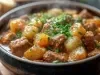 Imagem de um bowl escuro com a receita de picadinho de carne, batata e cenoura polvilhada com salsinha.