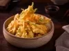 Imagem de um bowl rústico com tempurás de legumes crocantes e dourados.