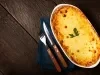 Fotografia mostra uma torta dourada, com a mussarela derretida e gratinada a coentro decorando.