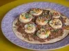 Fotografia de um prato roxo com a mini pizza com chocolate com rodelas de banan e granulado colorido.