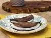 Fotografia em tons de marrom com um prato redondo ao centro. Em cima do prato existe duas panquecas de chocolate com aveia recheadas com um creme de iogurte.