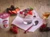 Fotografia em tons de rosa em uma bancada de madeira clara, um pote de vidro com o sorvete de frutas vermelhas, ao lado um potinho com mel e um pratinho com frutas vermelhas.