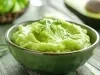 Em cima de uma mesa, tigela redonda verde com creme cremoso verde.