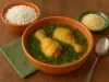 Foto da receita de frango servido num caldo de tucupi com folhas de jambu, tudo em uma tigela de barro laranja com acompanhamento de arroz e farinha de mandioca sobre a mesa