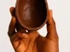 Fotografia em tons claros com um ovo de páscoa feito com chocolate meio amargo ao centro