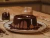 Imagem de um prato sobre uma bancada de madeira com um bolo de chocolate com calda de chocolate.