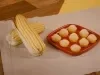 brigadeiros da farinha láctea sob prato vermelho ao lado de espigas de milho