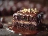 Fotografia de uma fatia de bolo de chocolate úmido, com recheio de caramelo e coberta por ganache brilhante. A superfície é adornada com granulado dourado e nozes, destacando-se em um fundo suavemente desfocado.