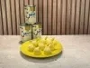 Docinhos cobertos com coco ralado em forminhas amarelas, servidos em prato amarelo com Leite Moça ao fundo.