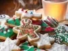 Em cima de uma mesa, prato redondo com biscoitos em formato de estrelas e árvore de Natal, decorados com glacê colorido e confeitos coloridos na cores vermelho, verde e branco.