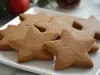 Em cima de uma mesa, prato redondo com biscoitos em formato de estrelas, decorados com açúcar cristal.