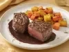 Dois bifes altos ao ponto servidos com molho reduzido escuro e raízes assadas douradas, apresentados em prato branco elegante
