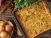 Fotografia de uma torta recém-assado em uma cozinha rústica, com cebolas caramelizadas e ervas, em uma bandeja dourada. Ao lado, cebolas inteiras e pimenta em grãos, criando um ambiente acolhedor e caseiro.