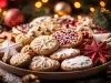 Em cima de uma mesa decorado com enfeites de natal, prato com biscoitos em formato de estrelas e redondos, decorados com glacê branco e vermelho.