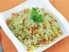 Em um prato branco, há arroz soltinho com uma mistura de legumes, como cenoura, ervilhas, milho, e pimentões, decorado com folhas de salsinha.
