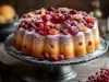 Fotografia de um bolo natalino em formato de anel, coberto com frutas secas como uvas-passas, cerejas e damascos, decorado com açúcar de confeiteiro e servido sobre um prato de metal.