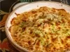 Em uma mesa, prato redondo com queijo gratinado, no meio do prato há um buraco com frango desfiado.