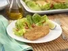 Imagem de um prato branco com um pedaço de sardinha frita com uma salada verde e um pedaço de limão.