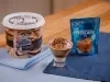 Taça com sorvete de chocolate ao lado de um pote de sorvete e de um sachê de NESCAFÉ® Ice.