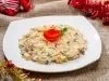 Em cima de uma mesa, prato com frango desfiado, cenouras raladas, milho e uvas-passas, decoradas com folhas de cheiro-verde e folho feita com cenoura.