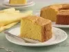 Fatia de bolo de milho macio e dourado servida em prato branco, com garfo ao lado e fundo aconchegante.