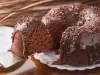 Imagem de um bolo de chocolate com cobertura de brigadeiro escorrendo e uma fatia do bolo sendo retirada com uma espátula.