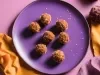 Fotografia em tons de roxo com um prato roxo ao centro. Dentro do prato existe pequenas trufas de cenoura com uva passa cobertas com coco ralado