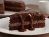 Um pedaço de bolo de chocolate com duas camadas de massa e um recheio de creme de chocolate ao centro. O bolo está coberto com uma generosa camada de calda de chocolate brilhante que escorre pelas laterais. Um pedaço de bolo de chocolate com duas camadas de massa e um recheio de creme de chocolate ao centro. O bolo está coberto com uma generosa camada de calda de chocolate brilhante que escorre pelas laterais.