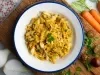 Em cima de uma mesa, prato redondo com porção de bacalhau desfiado com cebola, decorado com folha de salsa.