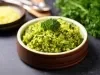 Em cima de uma mesa, um recipiente redondo com porção de arroz soltinho verde, decorado com um brócolis.