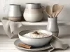 Em cima de uma mesa, tigela repleta de arroz doce cremoso, com uma textura suave e aveludada, decorado com canela em pó e anis estrelado.