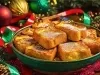 Em cima de uma mesa com bolinhas e pinhas de natal, prato com rabanadas, polvilhadas com açúcar de confeiteiro.