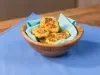 Fotografia em tons claros de uma mesa de madeira com um pano azul. Sobre o pano tem um recipiente de madeira fundo com um paninho azul claro com alguns nuggets saudáveis.