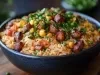 Em cima de uma mesa, tigela com porção de arroz soltinho com pedaços de bacon picado, milho e ervilha, decorado com cheiro-verde picados.