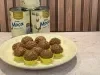Prato com docinhos cobertos com granulado de chocolate, em forminhas amarelas, e latas de Leite Moça ao fundo.