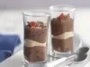fotografia em tons de cinza e marrom, contém dois copinhos transparentes com creme de chocolate e biscoitos de maisena